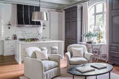 a living room filled with furniture next to a kitchen