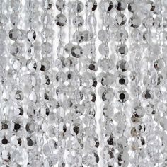 closeup of beads hanging from the ceiling in front of a white wall with black dots on it