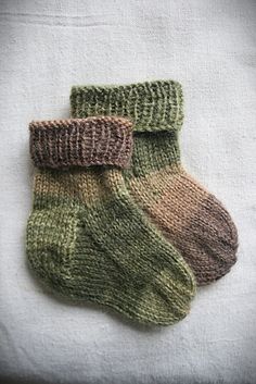 three pairs of knitted socks sitting on top of a white sheet