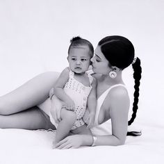 a woman holding a baby while laying on the ground