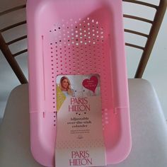 a pink plastic tray with a card in it on top of a white table next to a chair