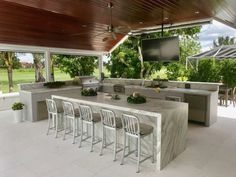 a large outdoor kitchen with an island and bar seating for eight people, under a covered patio