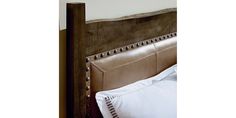 an upholstered headboard on a bed with white linens and brown leather