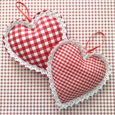 two red and white heart shaped ornaments on a checkered cloth tablecloth with lace