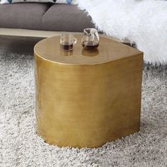 a coffee table with two glasses on it in front of a couch and rugs