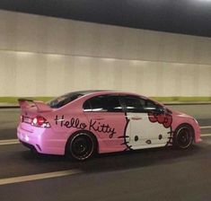 a pink car with hello kitty painted on it's side driving down the road