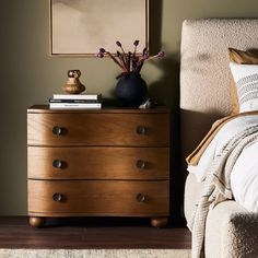 a bedroom with a bed, dresser and pictures on the wall