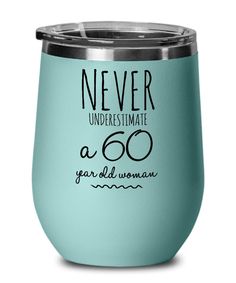 a teal colored wine tumbler with the words never underestmate 60 year old woman on it