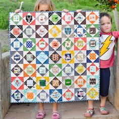 two young children holding up a quilt made with blocks