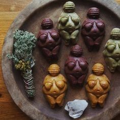 five small clay figures sitting on top of a wooden plate