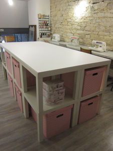 a white counter top with pink baskets on it in a room filled with desks and chairs