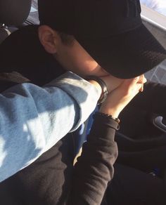 a man wearing a black hat sitting in the back seat of a car with his hands on his face