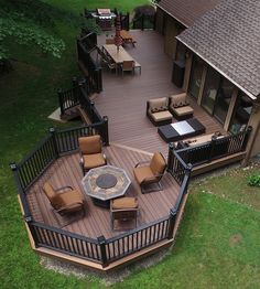 an aerial view of a deck with chairs and fire pit in the center, surrounded by green grass