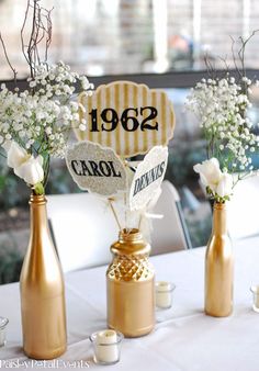 the table is set up with champagne bottles and flowers in vases on each side