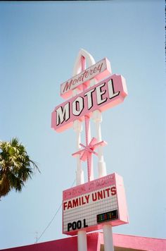 a pink motel sign with palm trees in the background