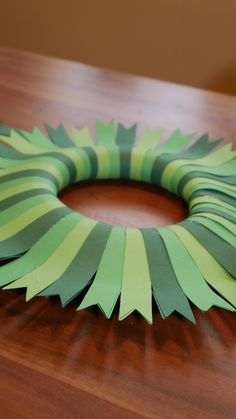 a green paper wreath sitting on top of a wooden table covered in strips of tape