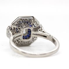 The Seraphina ring is a piece handmade in platinum which centers one emerald cut diamond of G color and VS1 clarity that weighs 0.50ctw. The center stone is surrounded by 24 old mine cut diamonds of G color and VS1 clarity that weigh 0.50ctw and 28 natural calibrated French cut sapphires that weigh 1.30ctw. Luxury Platinum Octagon Sapphire Ring, Luxury Octagon Sapphire Ring In Platinum, Luxury Octagon Sapphire Platinum Ring, Brilliant Cut Octagon Sapphire Ring In Platinum, Luxury Octagon Sapphire Ring With Brilliant Cut, Luxury Octagon Brilliant Cut Sapphire Ring, Gia Certified 14k White Gold Art Deco Ring, Art Deco Sapphire Ring With Gia Certified Diamond, Art Deco Gia Certified Sapphire Ring With Diamond