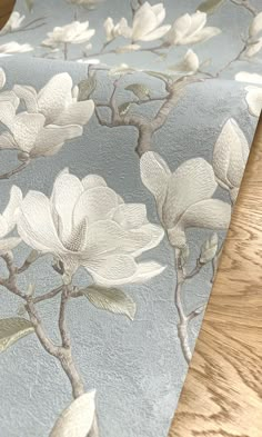 a close up of a table cloth with white flowers and leaves on blue background,