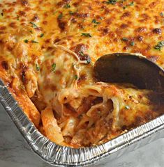 a casserole dish with meat and cheese being lifted from the pan by a spatula