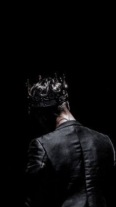 a man in a suit with a crown on his head looking down at the ground