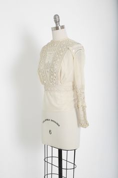 "Stunning Antique vintage early 1900's Edwardian crochet blouse Floral embroidered crochet lace, high neck long sleeve Natural cotton in ivory / cream button down back Great vintage condition - few age spots (see photos) very wearable M e a s u r e m e n t s: Size: fits like a XS S BUST: 18 1/2\" Waist: 13\" Total Length: 22\" Sleeves: 20\" Label: unbranded Fabric: cotton +All Measurements are taking while garment is lying flat+ + Jewelry, belts, and any other accessories are NOT included unless Fitted Victorian Tops With Lace Collar, Elegant Cotton Lace Daywear Top, Fitted Lace Top With Lace Sleeves For Daywear, Long Sleeve Lace Top For Daywear, Vintage Blouse With Lace Sleeves, Classic Fitted Long Sleeve Lace Top, Cream Long Sleeve Blouse With Lace Patchwork, Cream Long Sleeve Blouse With Lace Top, Cream Long Sleeve Wedding Top