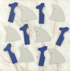 blue and white cupcake toppers are arranged on a marble table with the number one