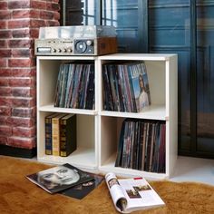 a record player sitting on top of a wooden shelf next to a pile of records