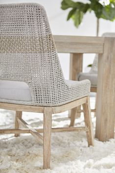 a close up of a chair near a table with chairs around it and a potted plant in the background