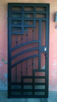 an iron gate is shown against a pink wall