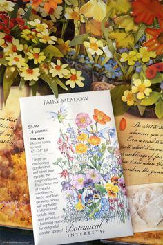 an open book sitting on top of a table next to flowers