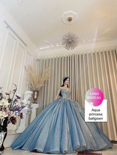 a woman in a blue ball gown standing next to a vase with flowers