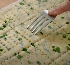 a person is using a fork to make ravioli with cheese and green onion sauce