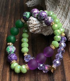 These two bracelets paired so well, we had to offer them as such! For the first Purple and Green bracelet we used four different types of beads. We started with a few 10mm  Purple Rainforest Agate beads, along with 8mm Green Crystal, 10mm Purple Frosted Glass, then completed it with 10mm Green Jade Agate beads...the results are stunning! Wear with anything!  The second bracelet in this ravishing duo to has the same 8mm Green Crystal beads paired with 8mm Purple Crystal Beads, then connected it all together with a dainty *limited edition* Star Charm. This is a lovely set, don't miss out! Price includes both bracelets.  Bead Size: 8mm, 10mm  Bead Type: Green Crystal, Purple Rainforest, Purple Frosted Glass, Purple Crystal. Beaded on a Grade-A Stretch Cord All items are packaged in a high-qua Cheap Green Bracelet, Affordable Green Crystal Bracelet With 8mm Beads, Cheap Green Wrap Bracelet As Gift, Green Charm Bracelet With Colorful Beads As Gift, Spiritual Green Bracelets With Colorful Beads, Green Beaded Bracelet With Spacer Beads For Friendship, Green Friendship Bracelets With 8mm Beads As Gift, Green Bracelets For Friendship, Green Hand-strung Bracelets For Friendship