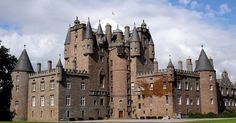 an old castle with towers and grass in front