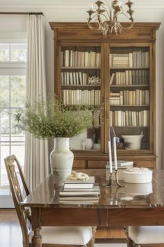 a dining room table and chairs with bookshelves in the background