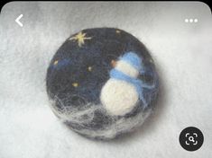 a felt snowman brooch sitting on top of white fabric