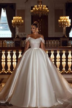 a woman in a white wedding dress standing on a stair case with chandeliers