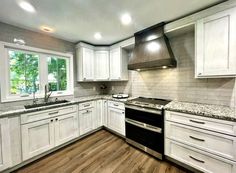 an empty kitchen with white cabinets and wood flooring is pictured in this image, there are lights on above the stove