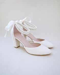 a pair of white shoes with pearls on them