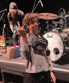 a man standing on top of a stage next to a drum kit and another person