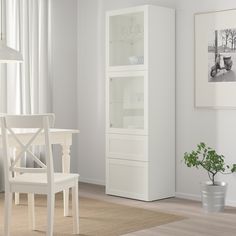 a dining room with white furniture and a potted plant