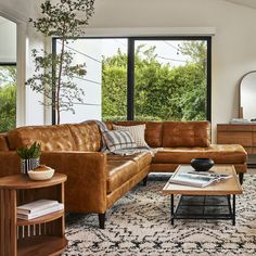 a living room filled with furniture and a large window overlooking the trees in the distance