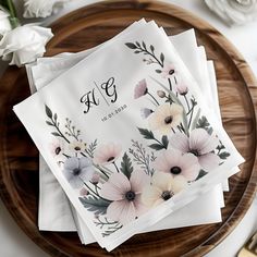 four napkins with flowers on them sitting on a wooden plate next to silverware