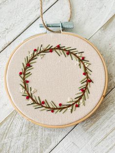 an embroidered wreath with red berries and greenery