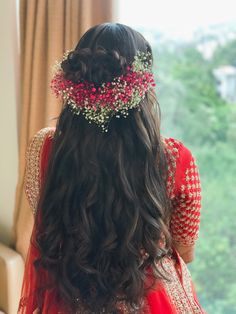 a woman with long dark hair wearing a red and gold headpiece in front of a window