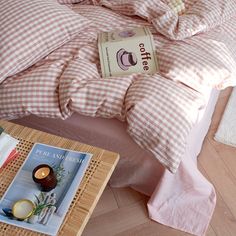 a bed with pink gingham comforter and pillows on it next to a coffee table