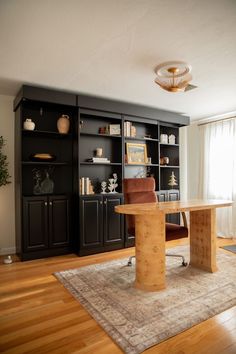 a living room filled with furniture and a large bookcase next to a window on top of a hard wood floor