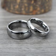 two wedding rings sitting on top of a wooden table