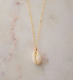 "Unleash your inner beach goddess with our Natural White Cowrie Shell Necklace! Handcrafted with a creamy-white cowrie shell, this piece is more than just a necklace--it's a conversation starter, a part of the ocean, a symbol of strength and prosperity. Perfect to uplift any outfit and designed to transport you to sunny shores, this necklace is sure give you summer vibes all year round.  We hand-make each necklace to order with a natural Cowrie shell that's set onto your choice of a sterling sil Dainty Shell Necklace For Beach, White Ocean-inspired Charm Necklace For Gift, Ocean-inspired White Charm Necklace As Gift, Ocean-inspired White Charm Necklace Gift, White Shell Charm Necklaces For The Beach, Dainty Shell Charm Necklace For Beach, White Shell Charm Necklace As Gift, White Shell Charm Necklace For Gift, White Shell-shaped Shell Jewelry