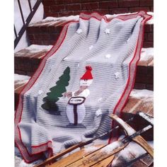 a knitted blanket with a christmas scene on it and sled next to it